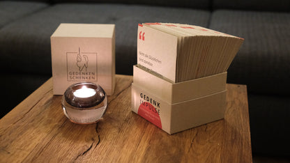 Trauergeschenk mit Gedenkimpulse-Karten und einer Kerze auf einem Holztisch.